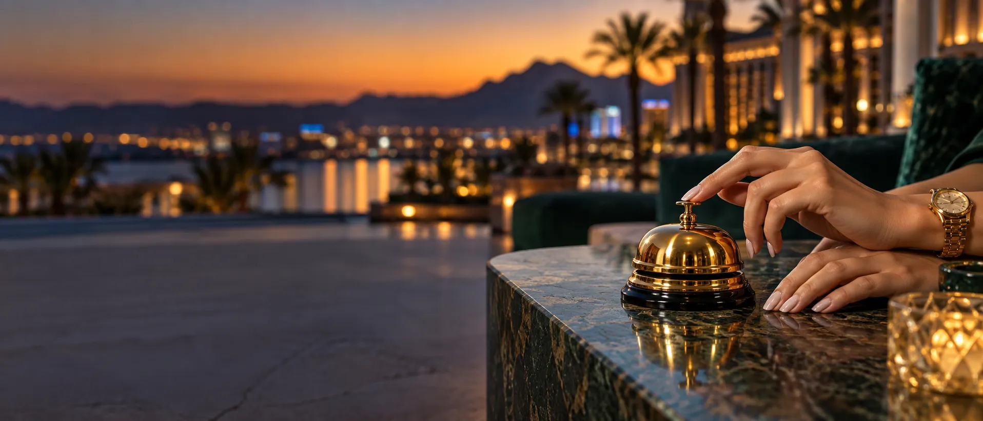 Hands resting beside a gold concierge bell at a desert resort, echoing quick answers before joining Here2Win Casino